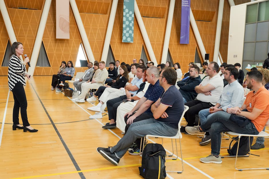 Speaker presenting to attentive audience in a modern hall with triangular decor.