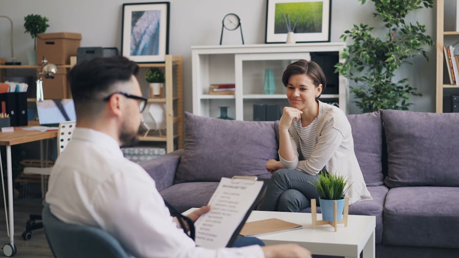A woman engages with a male therapist in a modern, cozy office setting.