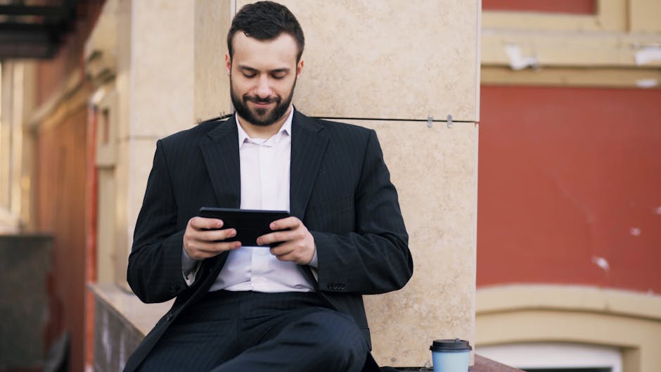 A man in a suit using a tablet outside while enjoying a coffee, with an urban backdrop.