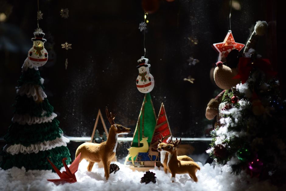 Charming Christmas window display featuring reindeer and snowman decorations with festive trees.