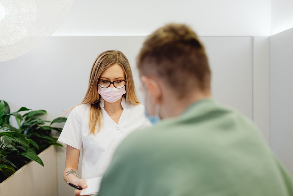 A medical professional with a face mask talking to a patient in a clinic setting.
